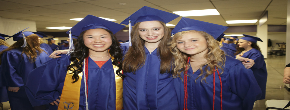 three girls in blue graduation caps and gowns.