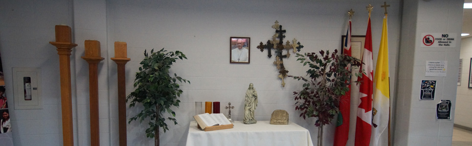 An alter, decorating with two fake trees on either side, a cross and a framed picture of the pope above it.
